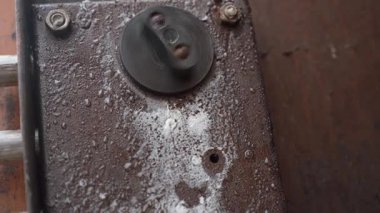 Eski, yıpranmış bir kapı kilidi mekanizmasının yakın çekim görüntüsü başparmak döndürme mekanizması ile açılıp kapanıyor, paslanmış metal çerçeveye giren ve çıkan güvenlik kilitlerini gösteriyor