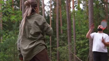 Güzel bir çam ormanında badminton oynayan genç atletik çift yaz tatillerinde dışarıda eğleniyor ve aktif ve sağlıklı bir yaşam tarzı sergiliyor.