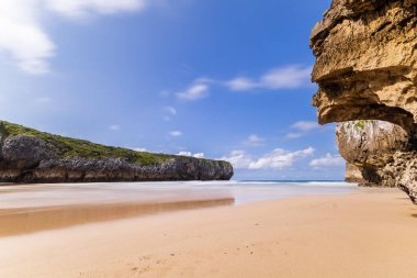 Güneşli bir günde, Atlantik Okyanusu tarafından kayalardan oyulmuş, ıssız bir kumlu Playa de Guadamia. Playa de Guadama, Llanes, Asturias, İspanya.