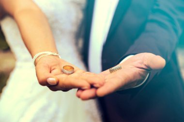 Yeni evlilerin elinde iki alyans. Altın alyanslar. Bir erkek ve bir kadının düğün töreninde değerli metallerden yapılmış alyanslar.. 