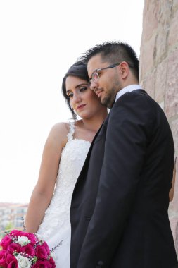 Gelin ve damat taş bir yel değirmeninin yanında poz veriyorlar. Aşk ve düğün kavramı