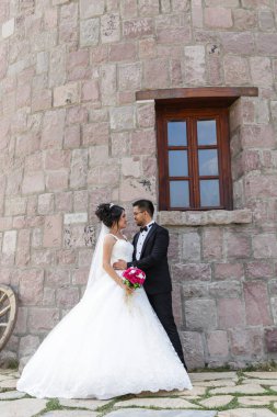 Gelin ve damat taş bir yel değirmeninin yanında poz veriyorlar. Aşk ve düğün kavramı