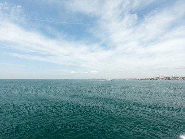 Mavi gökyüzü bulutlu ve dalgalı deniz kapanıyor gündüz vakti.