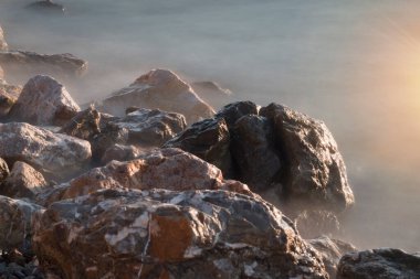 Deniz kenarında bir sürü kaya ve uzun pozlama. Ege denizi Balikesir Türkiye 'de uzun süre deniz ve kayalara maruz kaldı