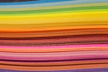 Renkli kağıt kıvrımlı şeritler parlak bir zemin oluşturuyor. Titrek gökkuşağı renkleri, yakın plan. Arkaplan için renkli soyut çizgiler.