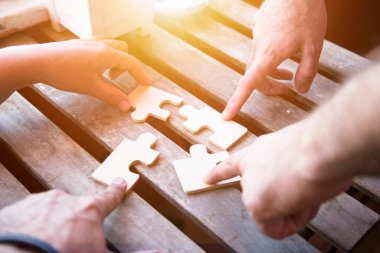 İş ortaklığı ya da iş adamlarıyla ortak çalışma kavramı. Bir bulmacayı çözmek için işbirliği yapan iş adamlarıyla ellerinizi kapayın..