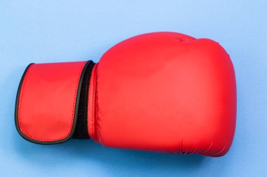 Mavi arka planda bir çift kırmızı deri boks eldiveni. 