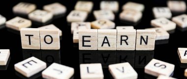 Siyah arkaplandaki ahşap harflerden yapılmış EARN metnine 