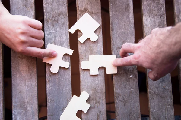 Business partnership or teamwork concept with a business people presenting a matching puzzle piece as they cooperate on finding an answer and solution, close up of their hands.