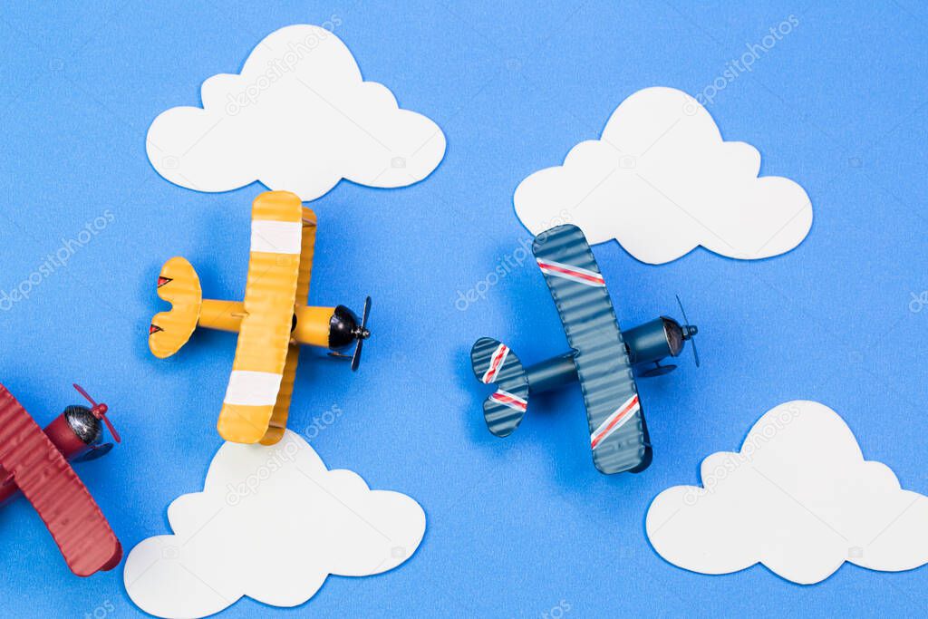 Toy airplanes on a background of blue sky with paper clouds