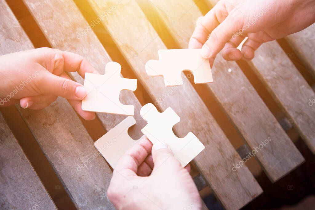 Business partnership or teamwork concept with a business people presenting a matching puzzle piece as they cooperate on finding an answer and solution, close up of their hands.