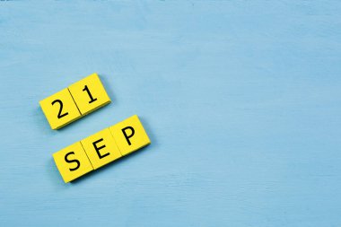 Mavi ahşap yüzeyde, 21 SEPTEMBER ve kopyalama alanı içeren sarı küpler takvimi