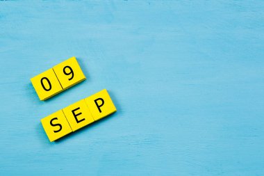 Mavi ahşap yüzeyde, 09 SEPTEMBER ve kopyalama alanı içeren sarı küpler takvimi