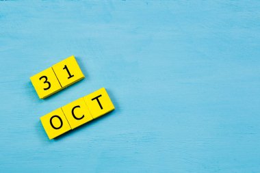 Mavi ahşap yüzeyde, 31 Ekim tarihli sarı küpler takvimi ve kopyalama alanı