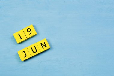 19 HAZİRAN ile mavi ahşap yüzeyde sarı küpler takvimi ve kopyalama alanı