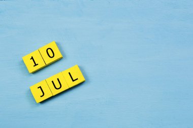 Mavi ahşap yüzeyde 10 Temmuz 'lu sarı küpler takvimi ve boşluk kopyala