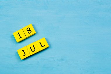 Mavi ahşap yüzeyde, 18 Temmuz 'lu sarı küpler takvimi ve boşluk kopyala