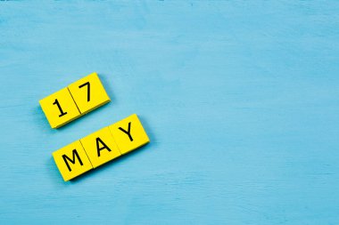 17 MAYIS ile mavi ahşap yüzey üzerinde sarı küpler takvimi ve kopyalama alanı