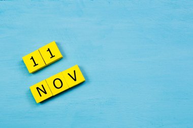 Mavi ahşap yüzeyde, 11 Kasım tarihli sarı küpler takvimi ve kopyalama alanı