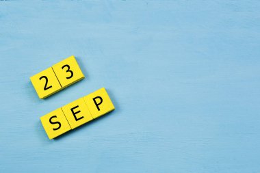 Mavi ahşap yüzeyde, 23 SEPTEMBER ve kopyalama alanı içeren sarı küpler takvimi