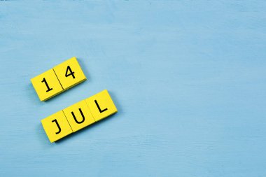 Mavi ahşap yüzeyde 14 Temmuz 'lu sarı küpler takvimi ve boşluk kopyala