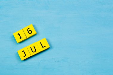 Mavi ahşap yüzeyde 16 Temmuz 'lu sarı küpler takvimi ve boşluğu kopyala