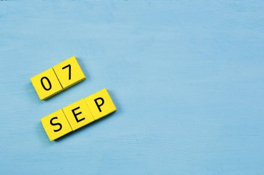 Mavi ahşap yüzeyli sarı küplü takvim 07 Eylül 'de ve boşluğu kopyala