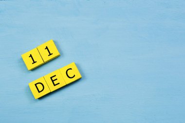 Mavi ahşap yüzeyde, 11 Aralık tarihli sarı küpler takvimi ve kopyalama alanı