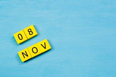 Mavi ahşap yüzeyde, 8 Kasım tarihli sarı küpler takvimi ve kopyalama alanı