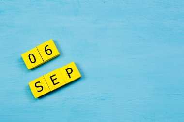 Mavi ahşap yüzeyli sarı küplü takvim 06 EPTEMBER ve kopyalama alanı
