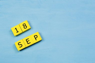 18 SEPTEMBER ile mavi ahşap yüzey üzerinde sarı küp takvimi ve kopyalama alanı