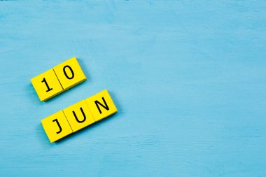 10 HAZİRAN ile mavi ahşap yüzey üzerinde sarı küpler takvimi ve kopyalama alanı