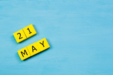 Mavi ahşap yüzeyde, 21 Mayıs 'lı sarı küpler takvimi ve kopyalama alanı