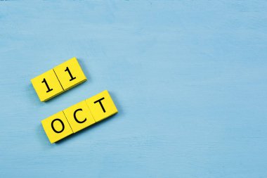Mavi ahşap yüzeyde, 11 Ekim tarihli sarı küpler takvimi ve kopyalama alanı