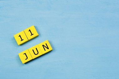 11 HAZİRAN ile mavi ahşap yüzeyde sarı küpler takvimi ve kopyalama alanı