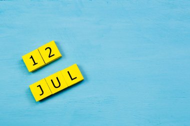 Mavi ahşap yüzeyde 12 Temmuz 'lu sarı küpler takvimi ve boşluk kopyala