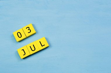 Mavi ahşap yüzeydeki sarı küpler takvimi 03 Temmuz 'da kopyala