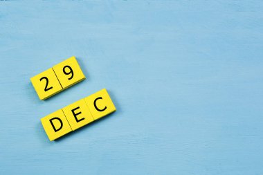 Mavi ahşap yüzeyde 29 Aralık tarihli sarı küpler takvimi ve kopyalama alanı