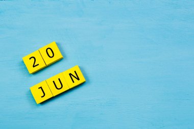20 HAZİRAN ile mavi ahşap yüzey üzerinde sarı küpler takvimi ve kopyalama alanı