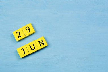 Mavi ahşap yüzeyde 29 Haziran 'lı sarı küpler takvimi ve kopyalama alanı