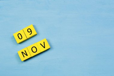 Mavi ahşap yüzeyde, 09 NOVEMBER ve kopyalama alanı içeren sarı küpler takvimi