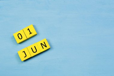Mavi ahşap yüzeyli sarı küplü takvim 01 Haziran ve kopyalama alanı