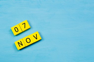 Mavi ahşap yüzeyli sarı küplü takvim 07 NOVEMBER ve kopyalama alanı