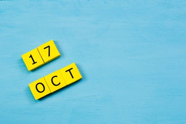 17 Ekim tarihli mavi ahşap yüzeyde sarı küpler takvimi ve kopyalama alanı