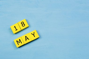18 MAY ve kopyalama alanı ile mavi ahşap yüzeyde sarı küpler takvimi