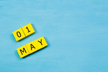 Mavi ahşap yüzeydeki sarı küpler takvimi 01 MAY ile kopyala