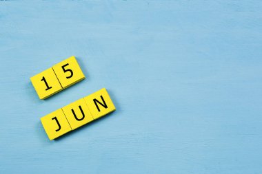 Mavi ahşap yüzeyde 15 Haziran 'lı sarı küpler takvimi ve kopyalama alanı