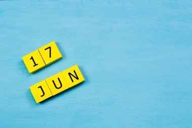 17 HAZİRAN ile mavi ahşap yüzey üzerinde sarı küpler takvimi ve kopyalama alanı