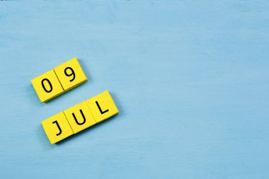 Mavi ahşap yüzeydeki sarı küpler takvimi 09 Temmuz 'da kopyala
