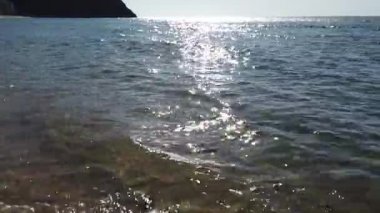 Çakıl taşlarında dalgalar kopuyor. Deniz sörfü. Dalgalar kıyı çakıl taşında ilerliyor. Yaz günü deniz ve sahil tatili konsepti 